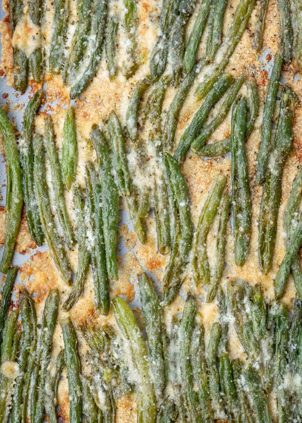 overhead image of smashed green beans with crispy cheese on baking sheet