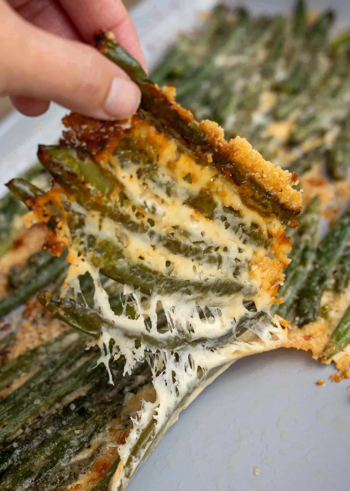 cheesy, smashed green beans being pulled from baking sheet