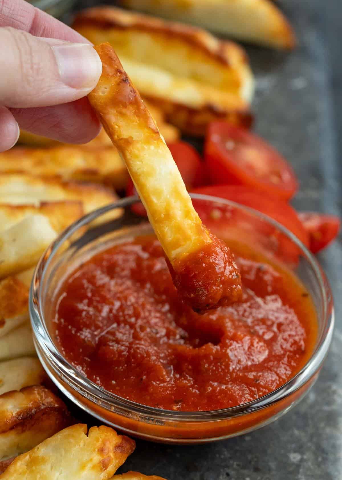 close up image of a halloumi fry being dipped in marinara