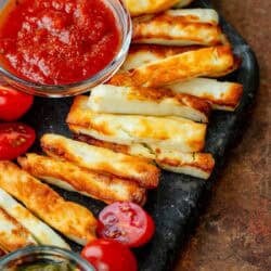 angled, overhead image of halloumi fries and marinara on black cutting board
