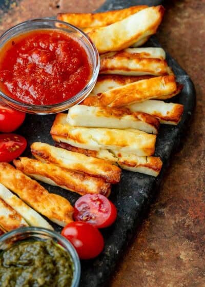 angled, overhead image of halloumi fries and marinara on black cutting board