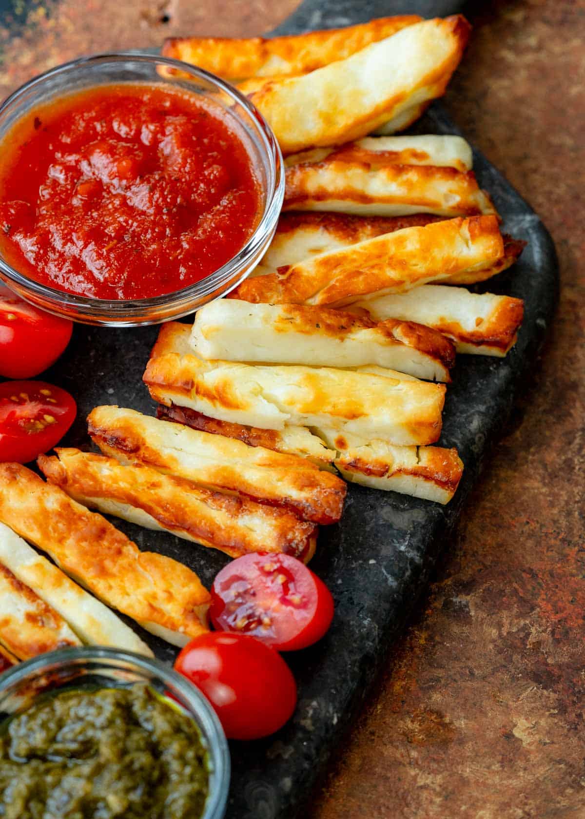 angled, overhead image of halloumi fries and marinara on black cutting board