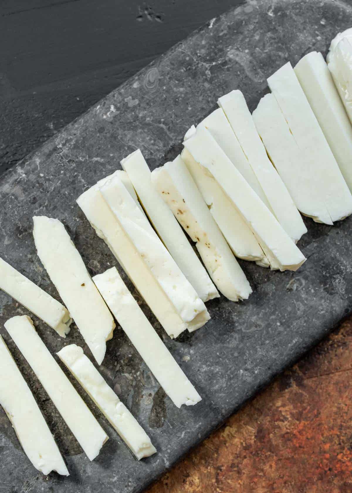 halloumi sliced on black cutting board