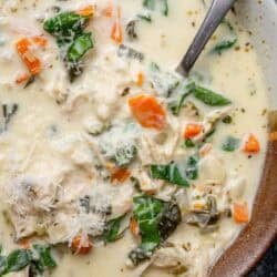 overhead image of chicken florentine soup in a brown and white bowl with a spoon