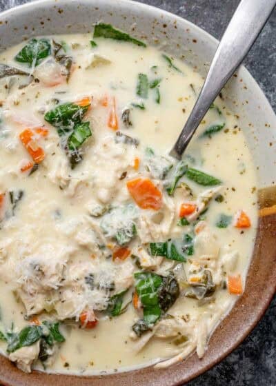 overhead image of chicken florentine soup in a brown and white bowl with a spoon
