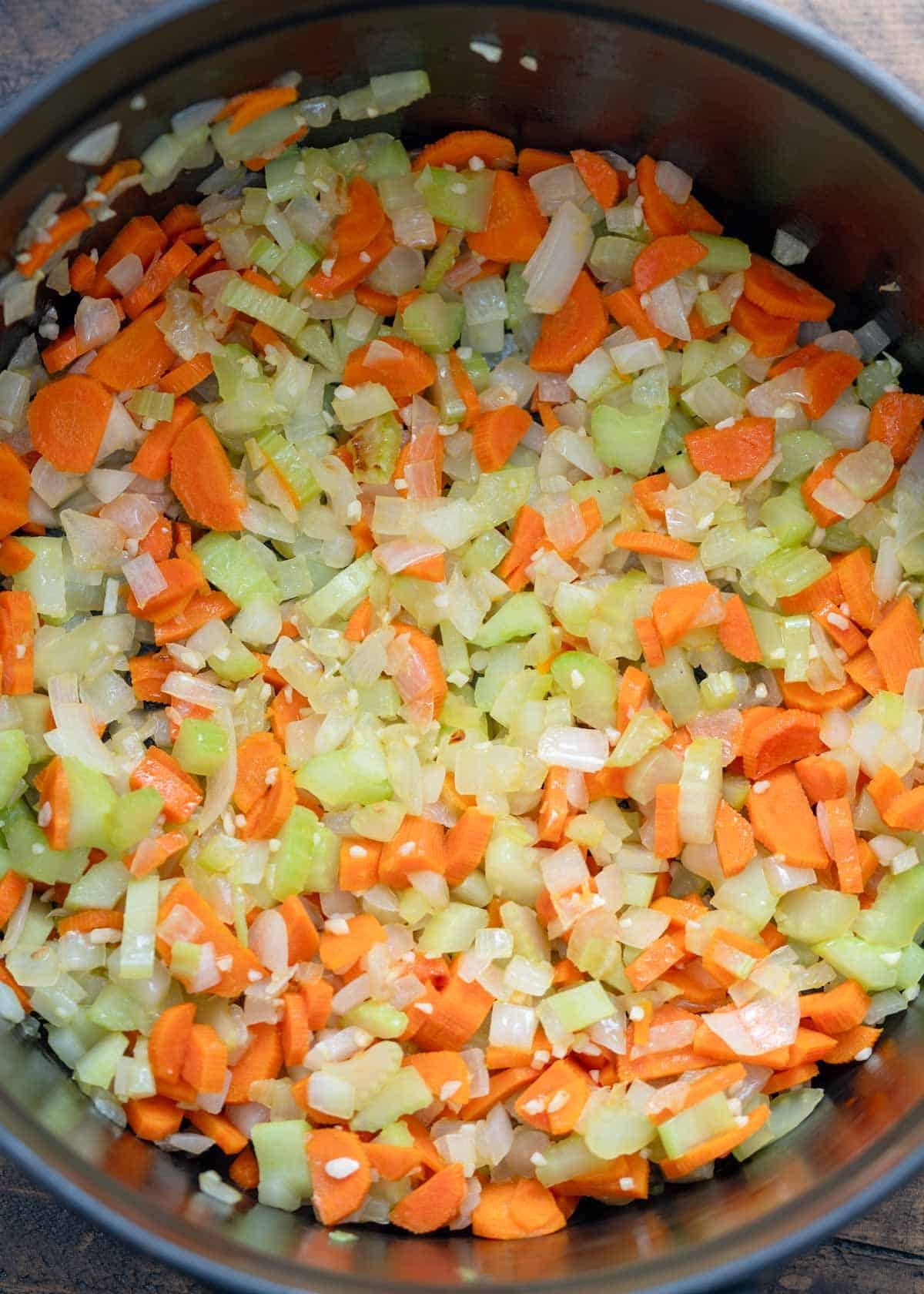 diced vegetables being added to black dutch oven