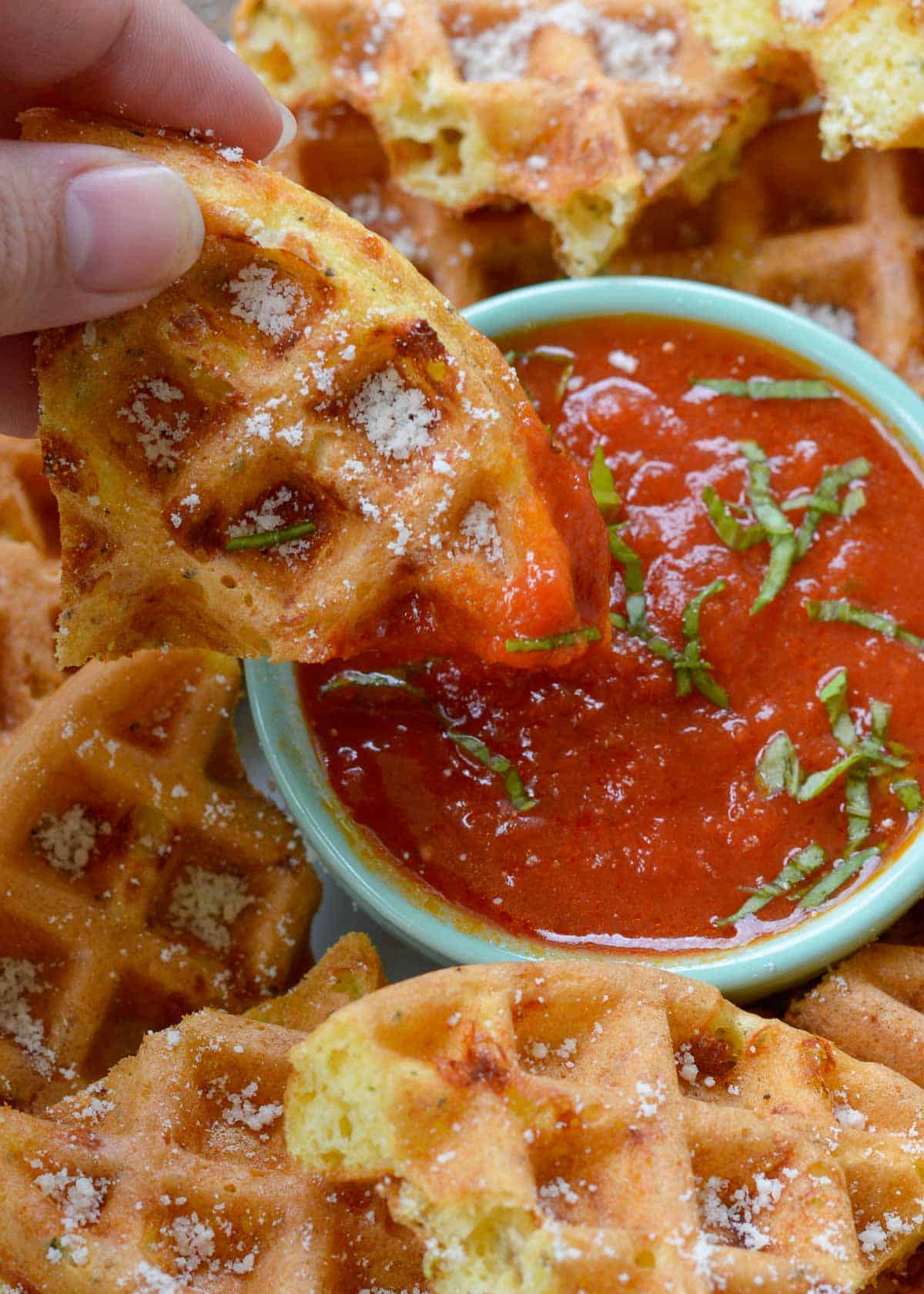 parmesan chaffles being dipped in marinara sauce