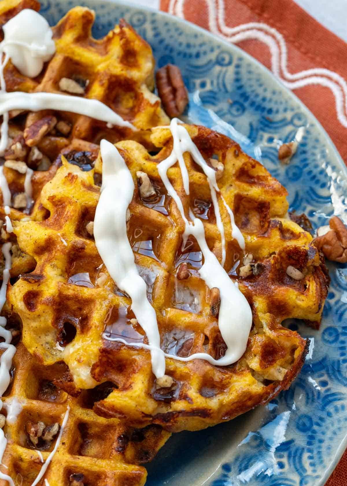 close up image of a pumpkin chaffle on blue plate after adding cream cheese glaze