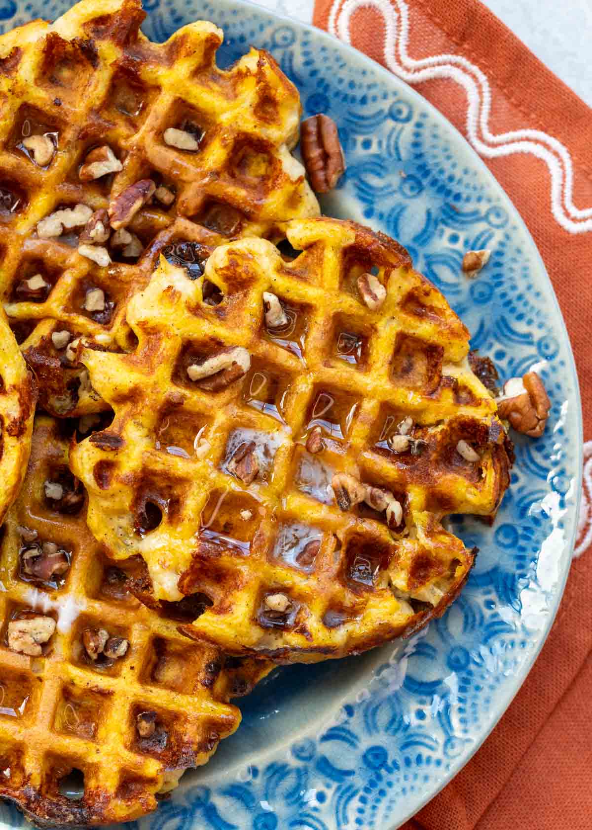 overhead image of three pumpkin chaffles on a blue plate