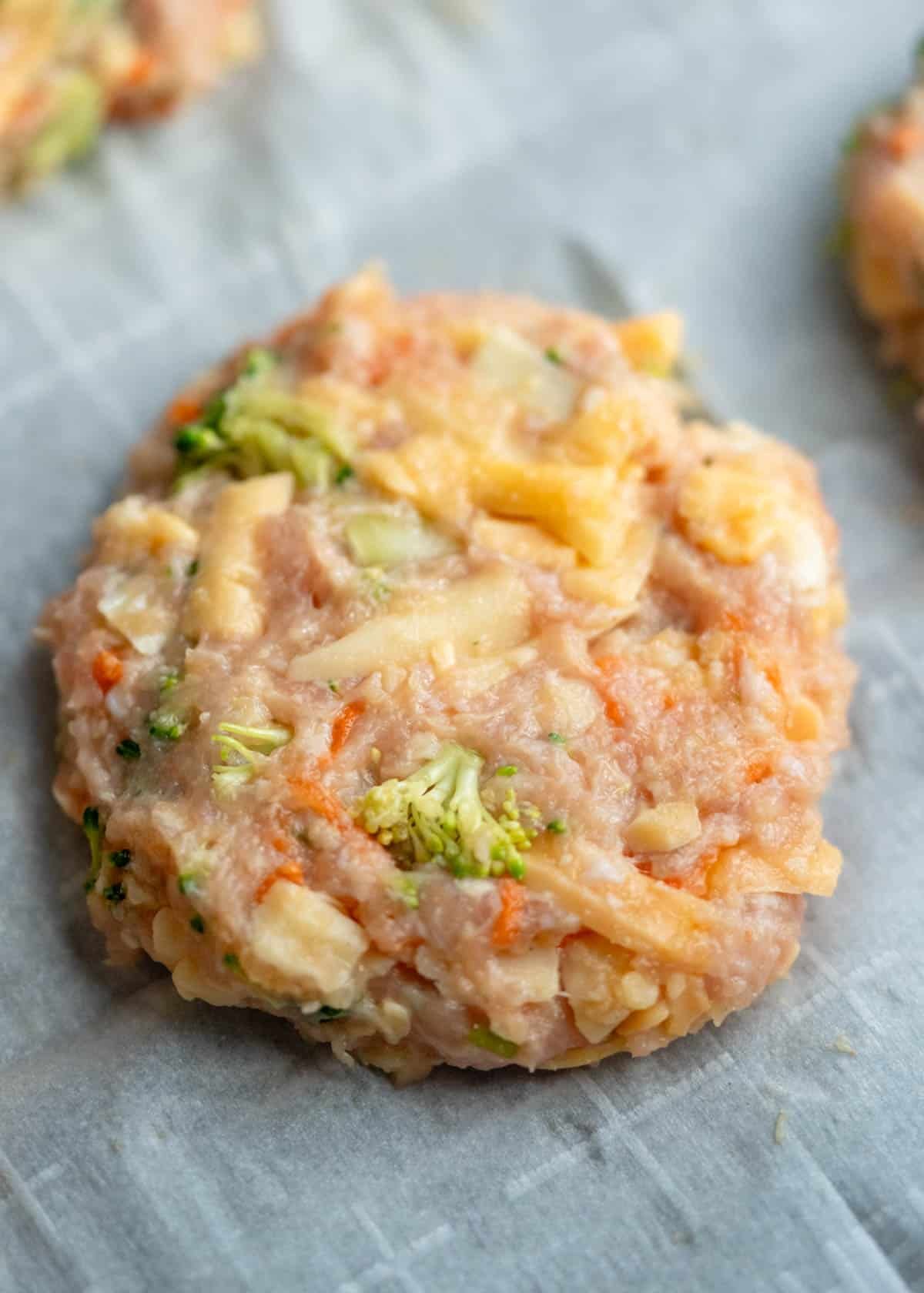 a broccoli cheddar chicken fritter patted out on cutting board