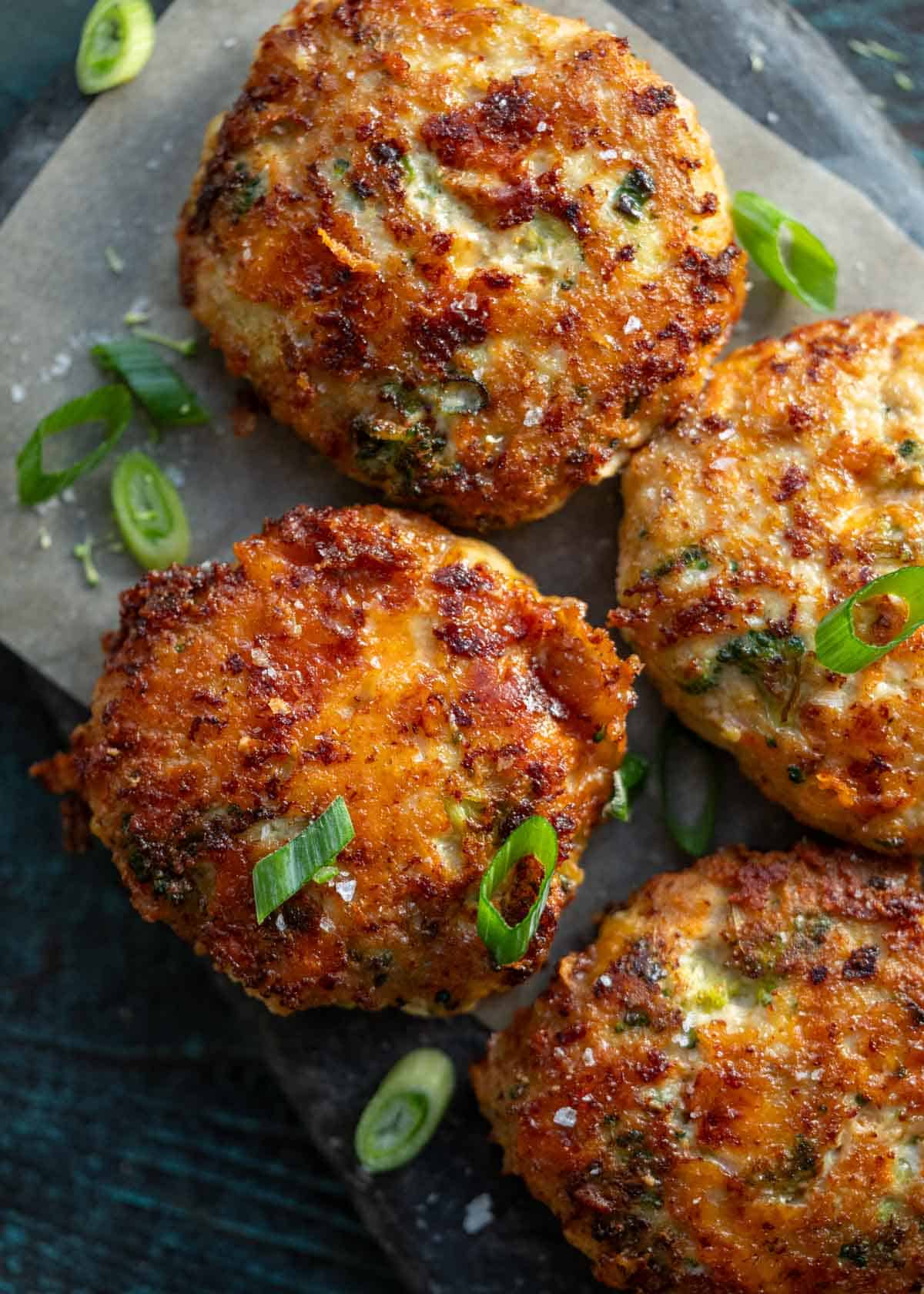 overhead image of four broccoli cheddar chicken fritters on gray cutting board