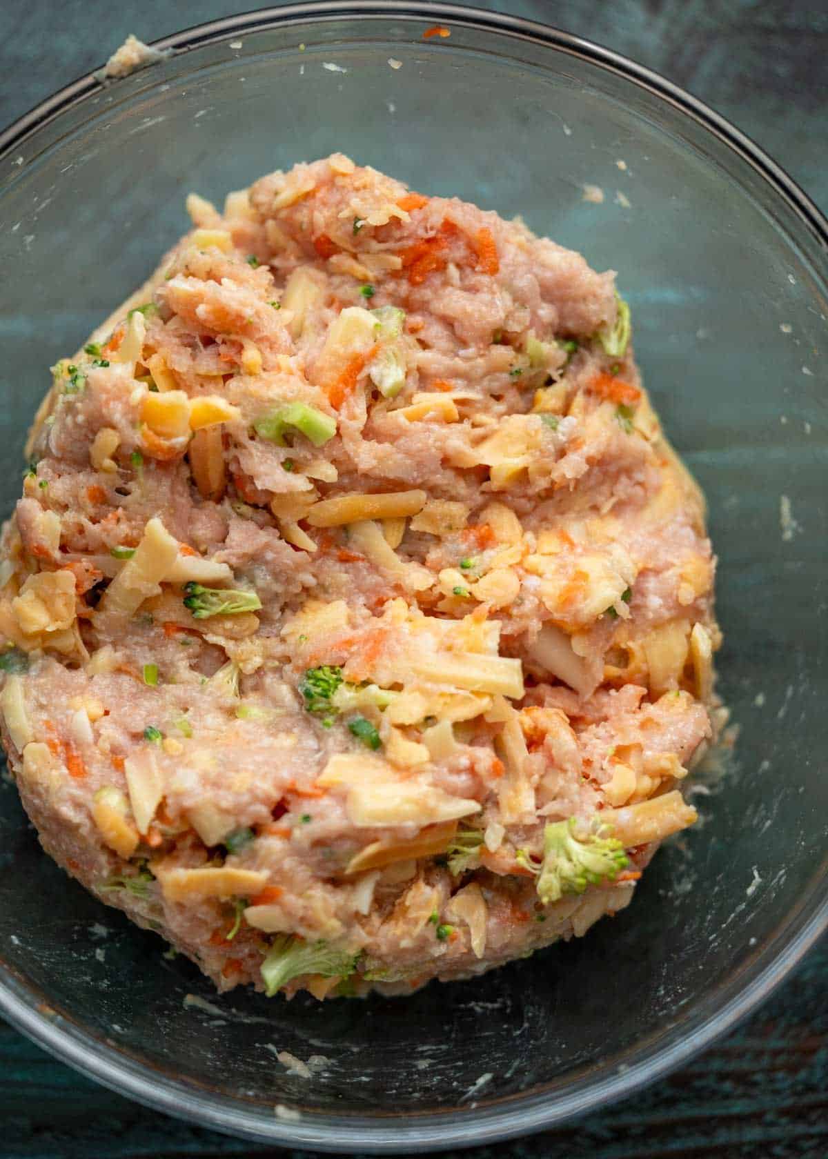 broccoli cheddar chicken fritter mixture in a clear mixing bowl