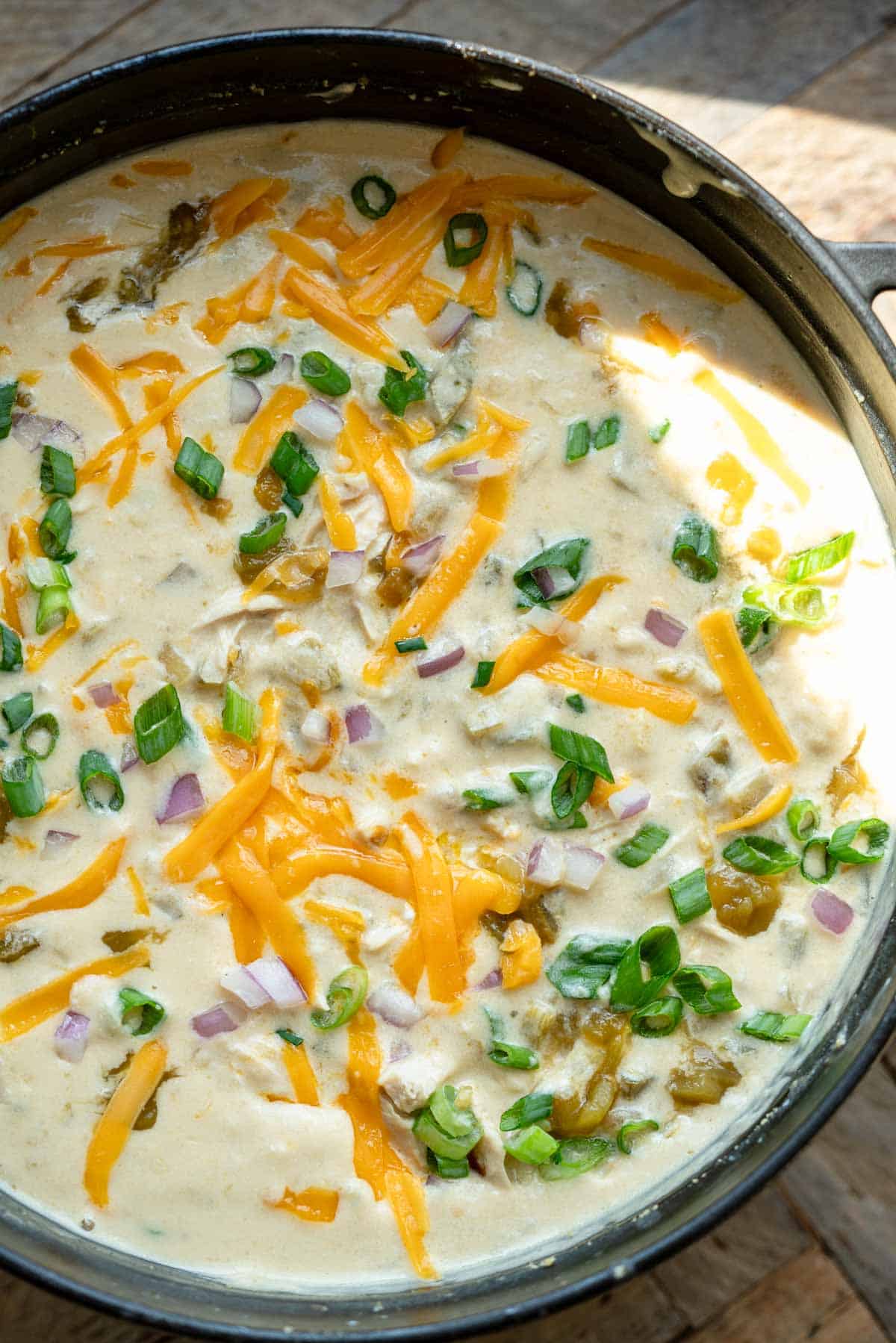 overhead image of chicken soup with green chiles in a black dutch oven