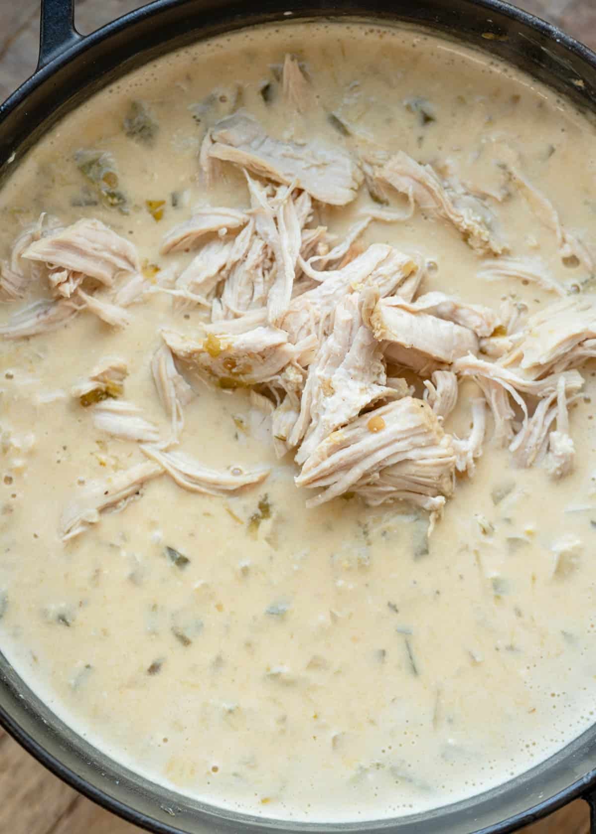 shredded chicken being added back to green chile chicken soup