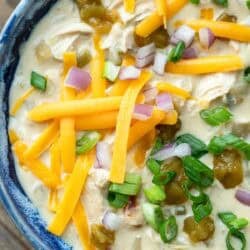 close, overhead image of chicken soup with green chiles in a blue bowl