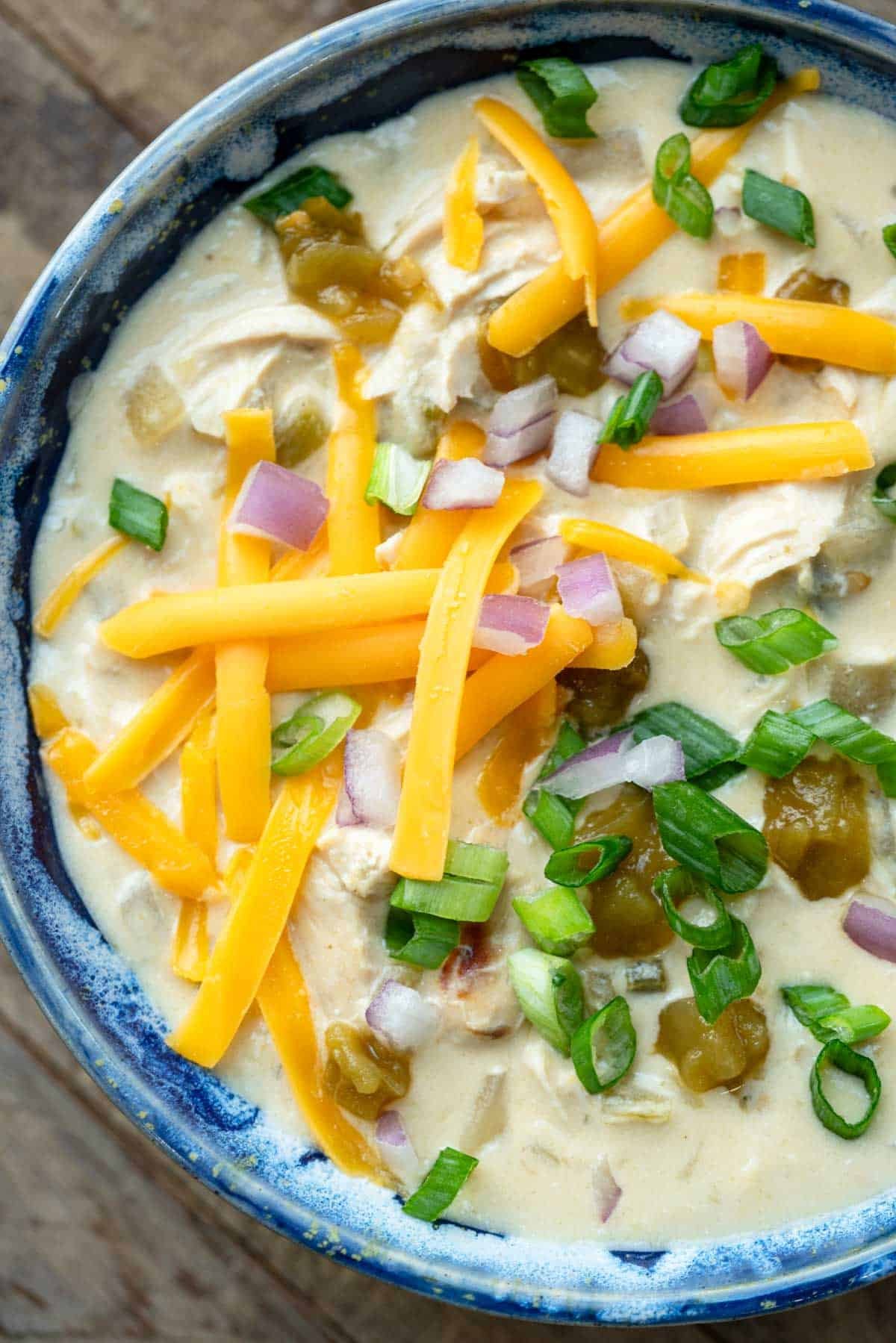 close, overhead image of chicken soup with green chiles in a blue bowl