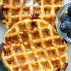 overhead image of cottage cheese chaffles stacked with blueberries in clear bowl