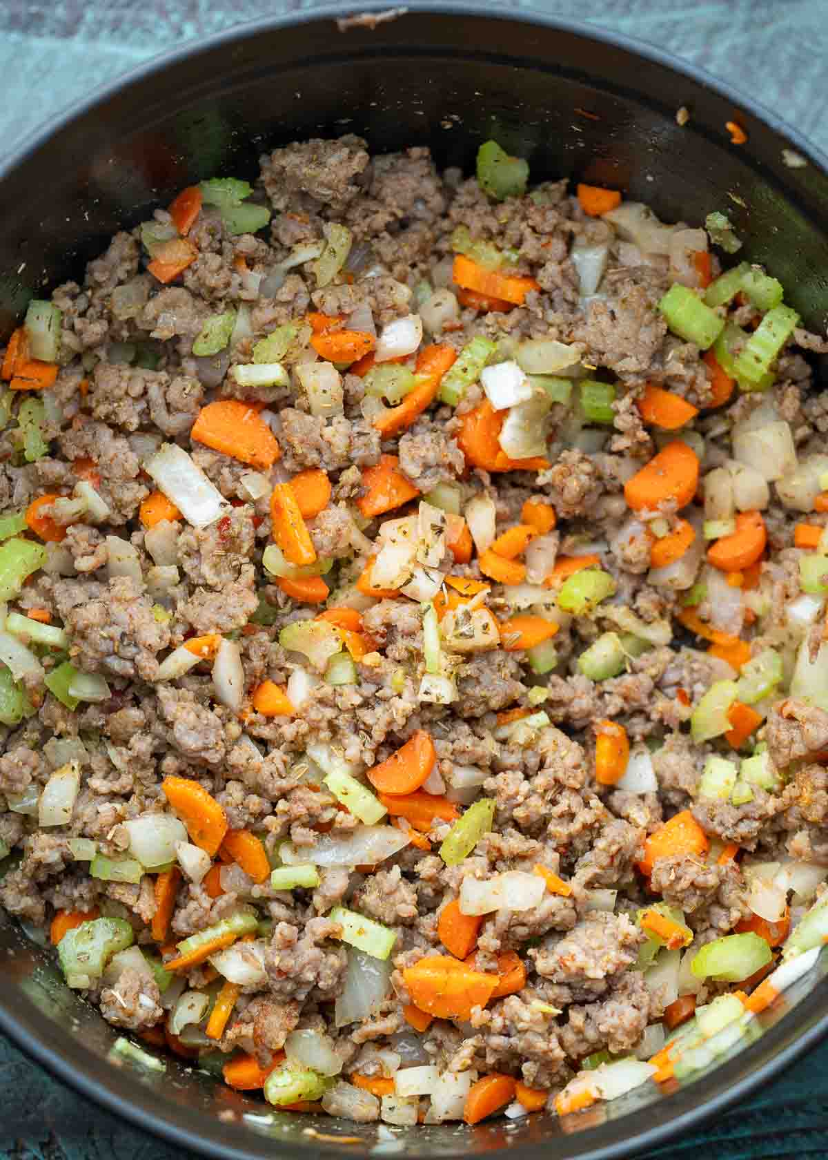 Italian sausage and veggies cooking in a black dutch oven