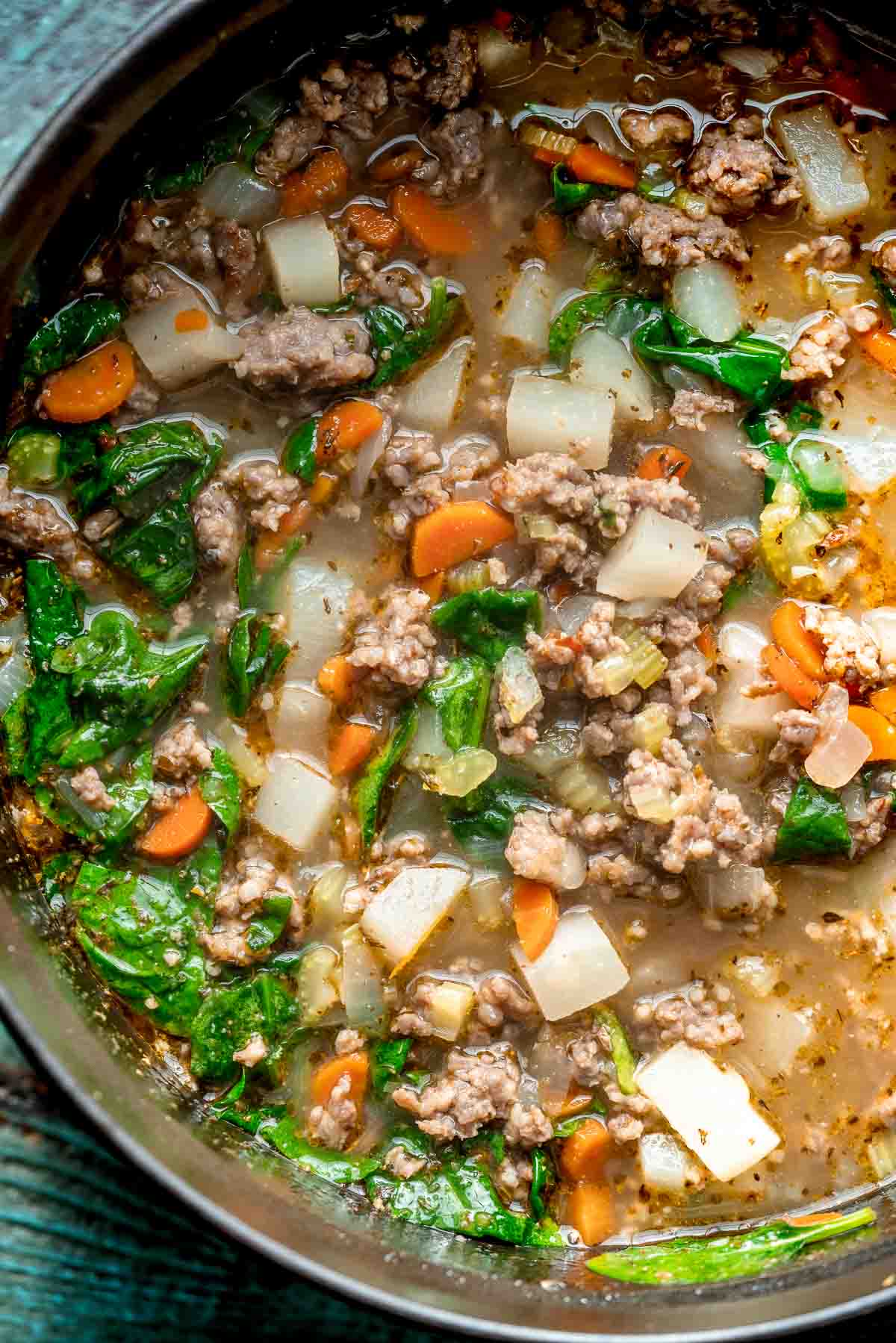 overhead image of Italian sausage soup cooking in a black dutch oven