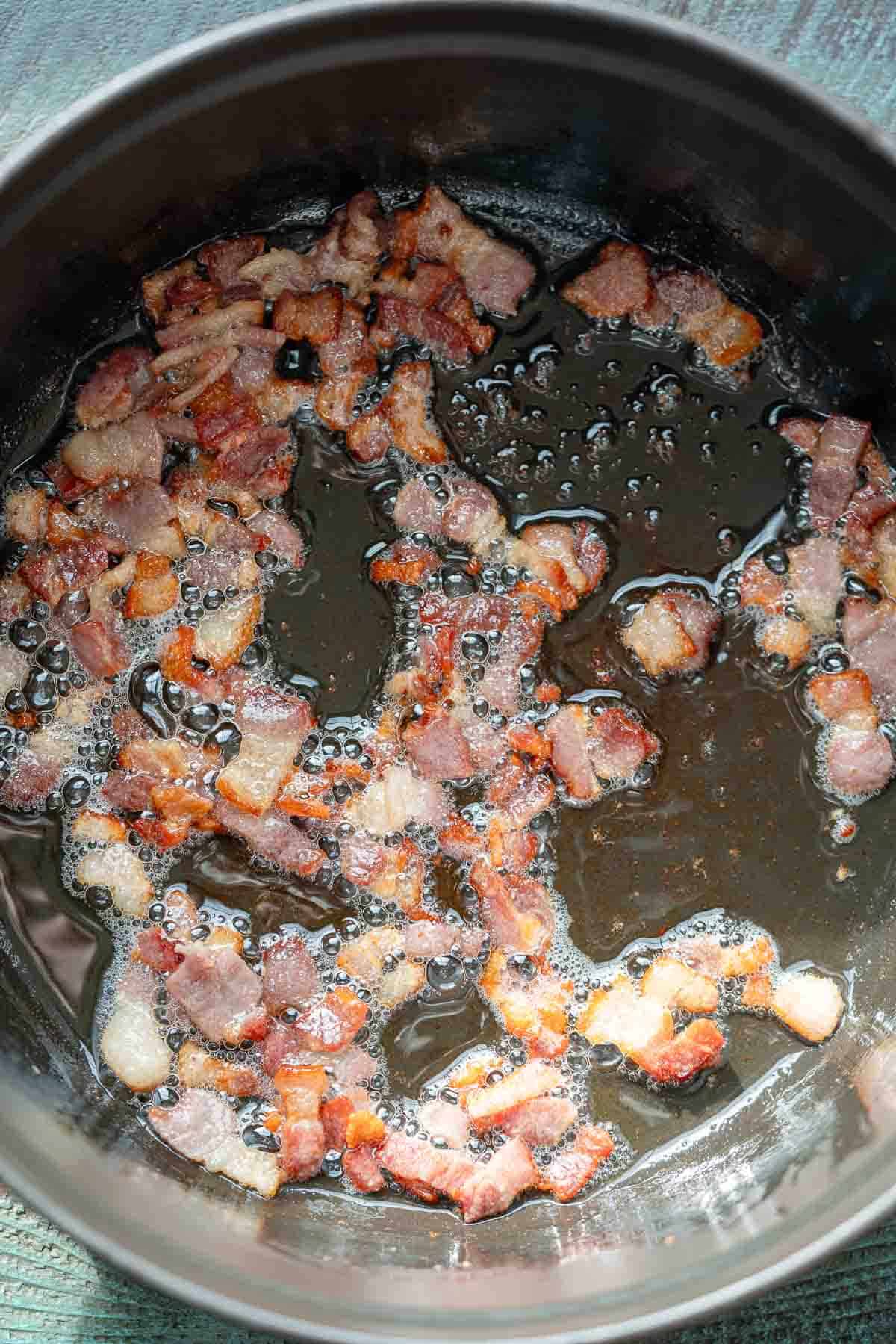 overhead image of bacon cooking in a dutch oven