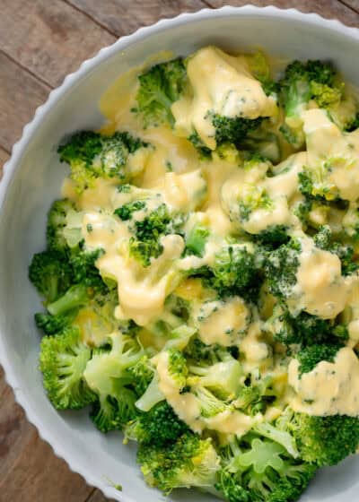 overhead image of broccoli and cheese sauce in a white bowl