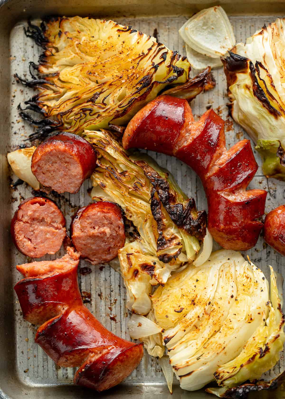 cooked sausage and cabbage sheet pan with some sausage sliced into pieces