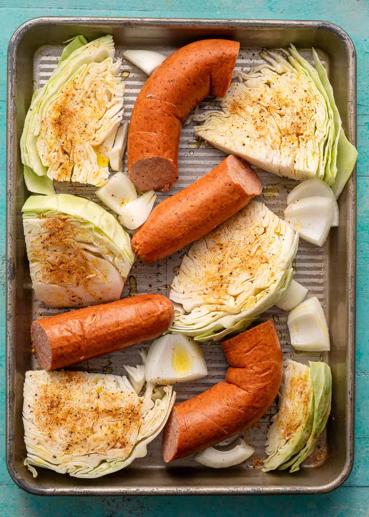 overhead image of uncooked sausage and cabbage sheet pan
