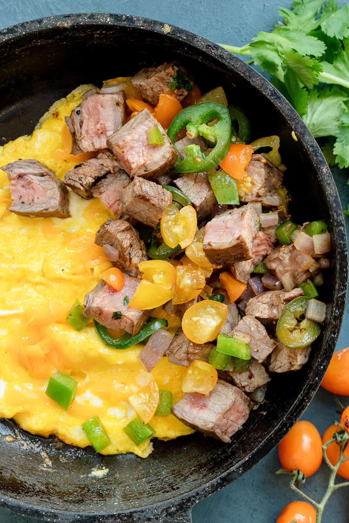 eggs, steak, and veggies in a cast iron skillet