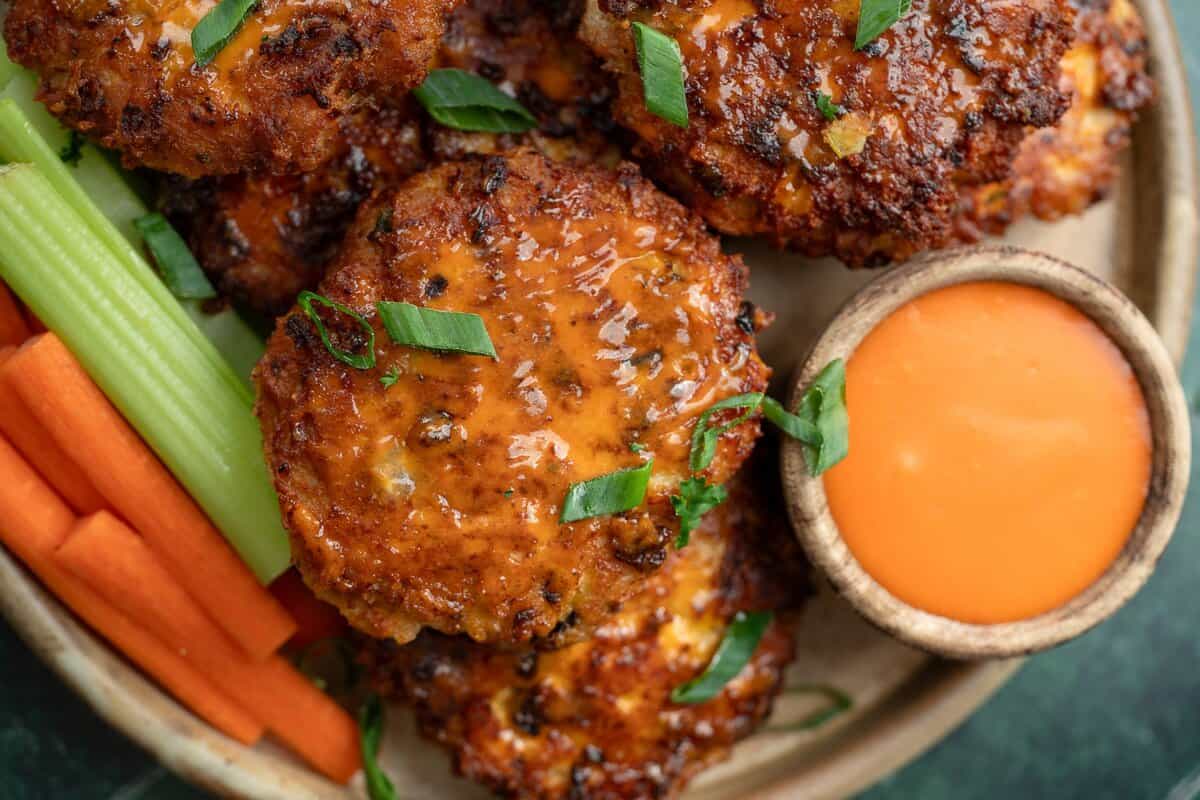 close up image of buffalo chicken fritters on plate with buffalo sauce