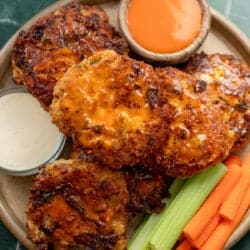 overhead image of buffalo chicken fritters stacked on plate with vegetables