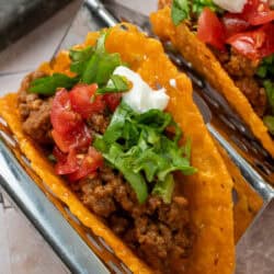 an image of a keto taco being topped with tomatoes and lettuce on a taco rack