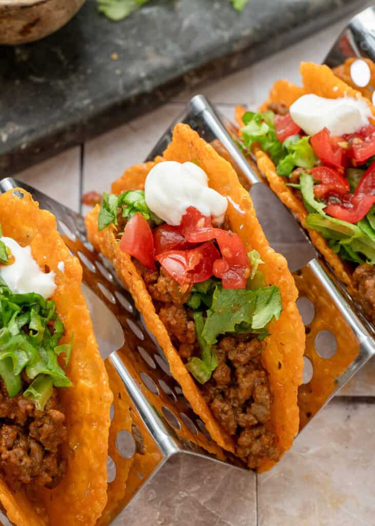 three keto tacos with lettuce and tomato on a taco rack
