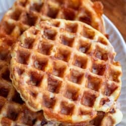 Overhead image of ham and cheese chaffles stacked on a white plate