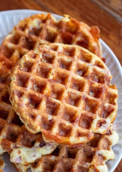 Overhead image of ham and cheese chaffles stacked on a white plate