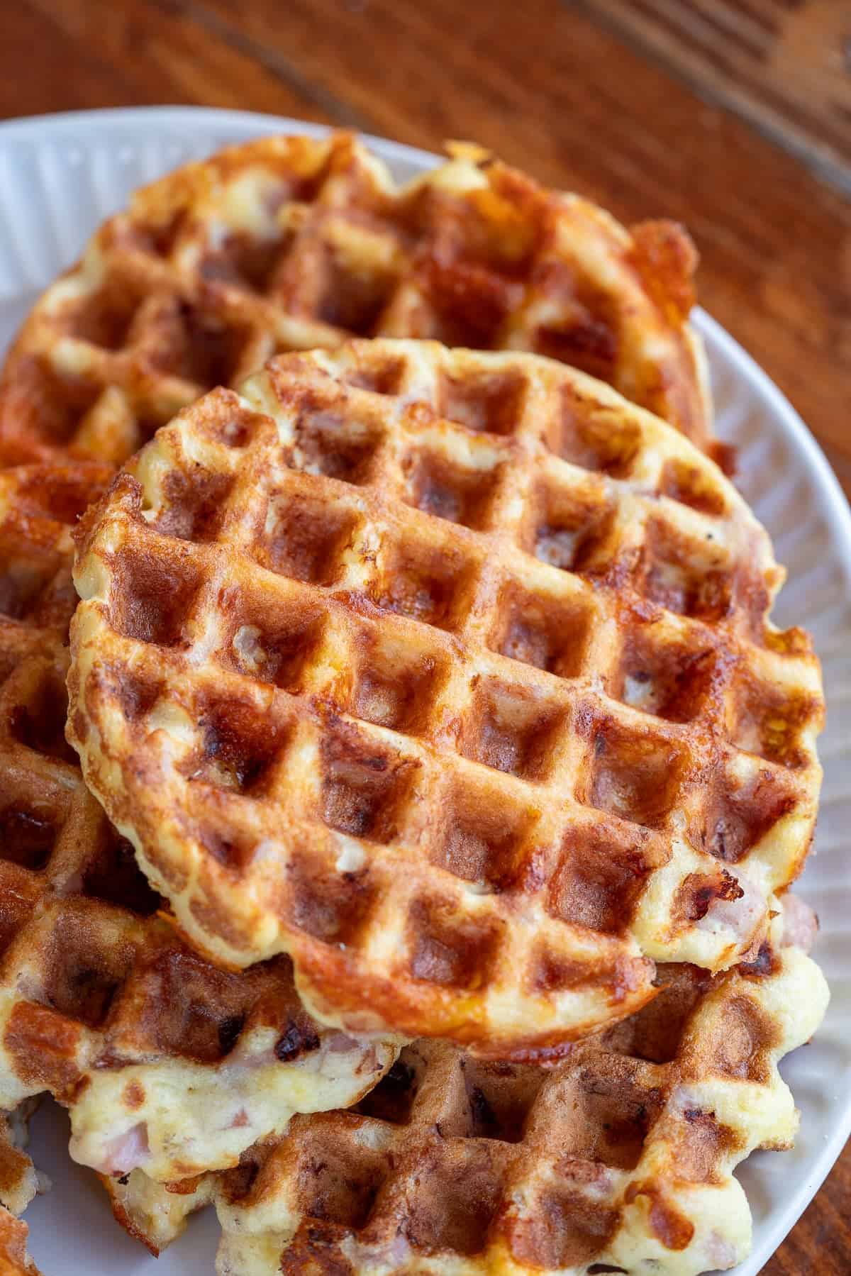 Overhead image of ham and cheese chaffles stacked on a white plate