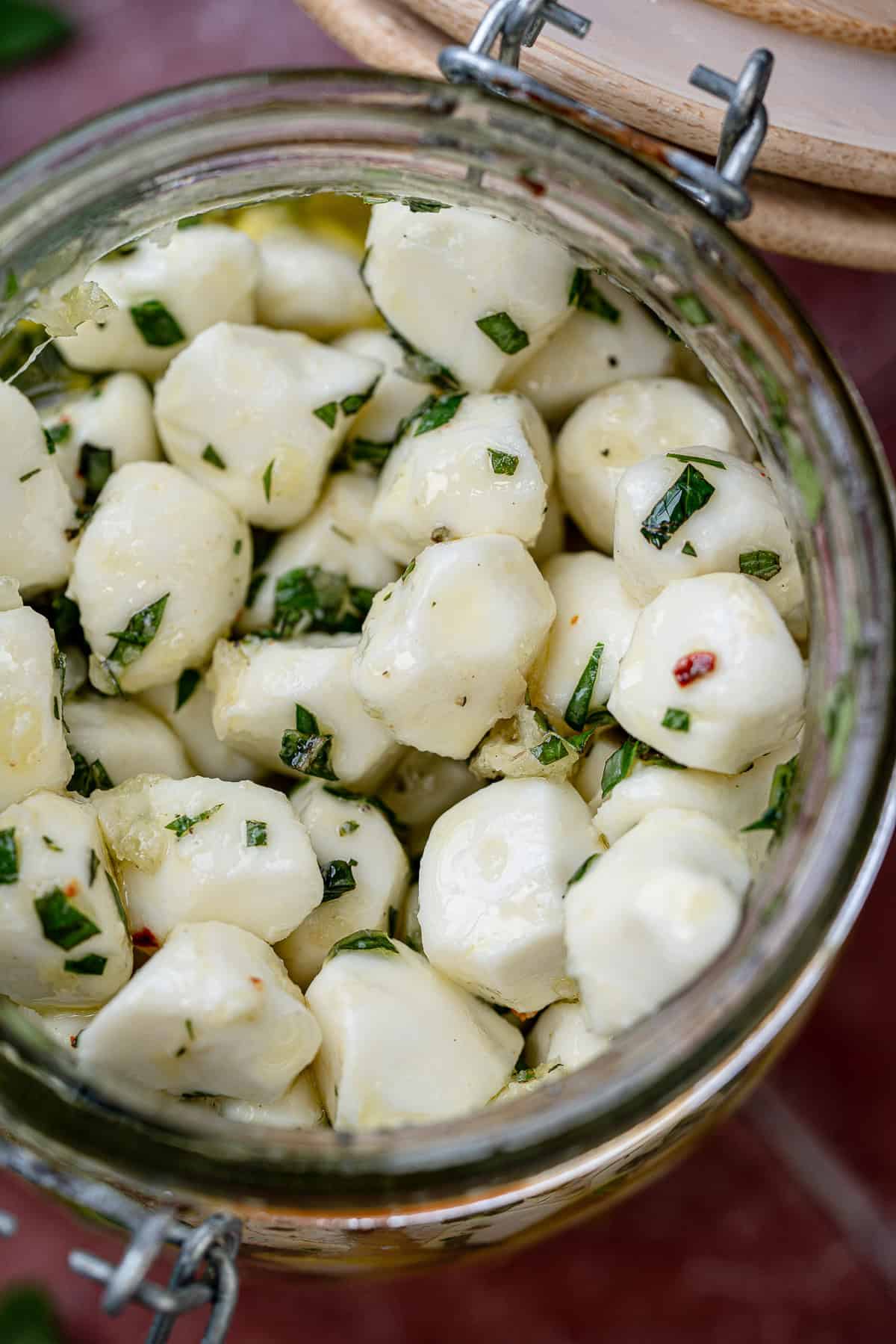 overhead image of marinated mozzarella pearls in a clear jar