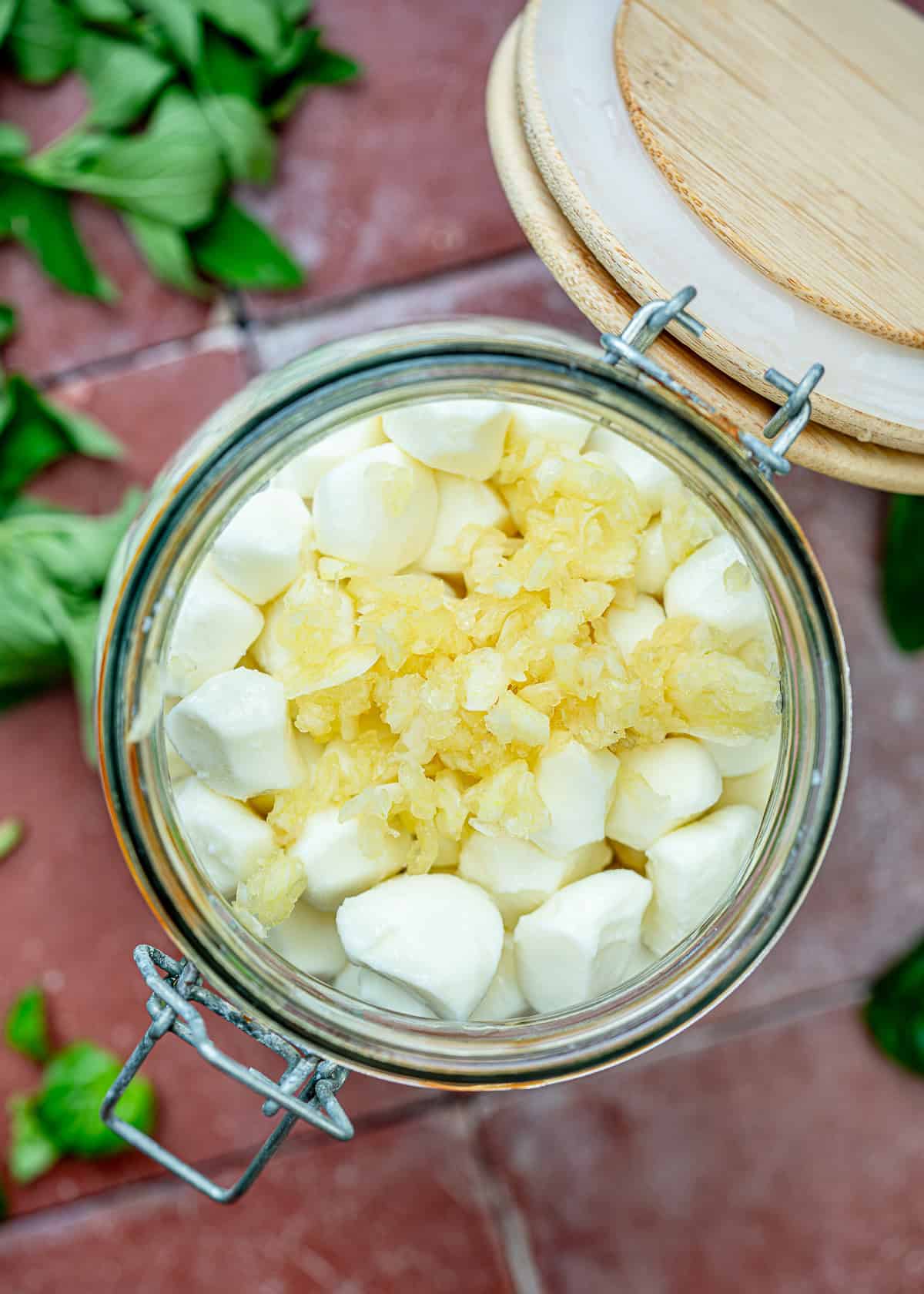 overhead image of mozzarella pearls in a jar before adding additional ingredients for mozzarella pearls recipe