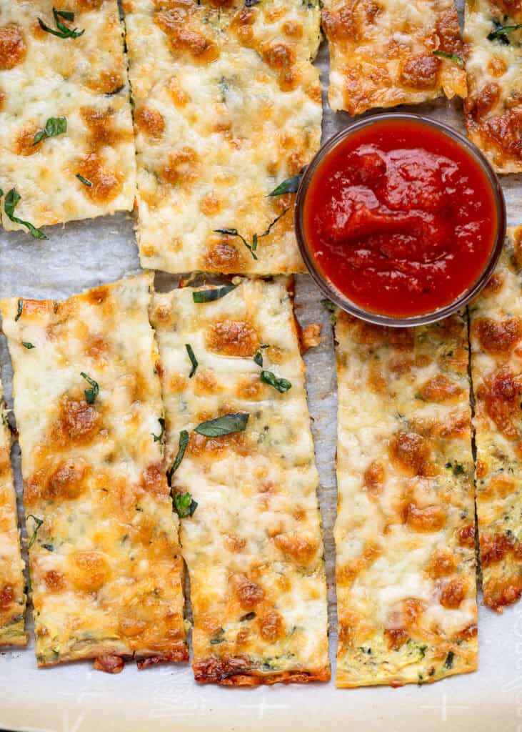 overhead image of zucchini breadsticks and small bowl of marinara sauce