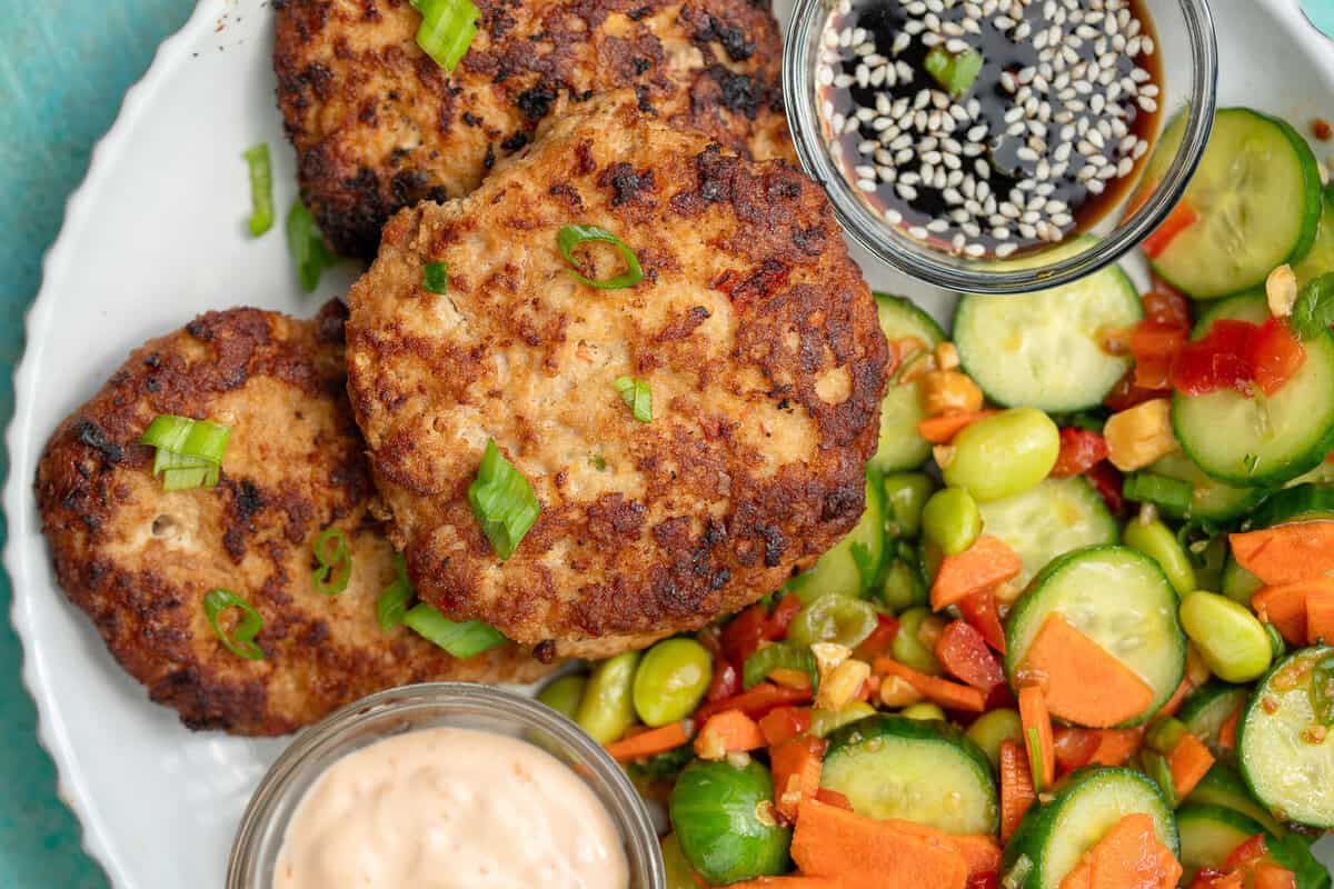 overhead shot of asian chicken fritters with cucumber salad on the side