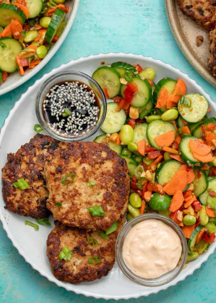 an overhead shot of Asian Chicken fritters on a white plate with a side of cucumber salad