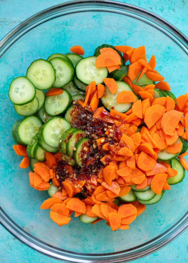 an overhead shot of the ingredients needed for a cucumber salad in a glass bowl