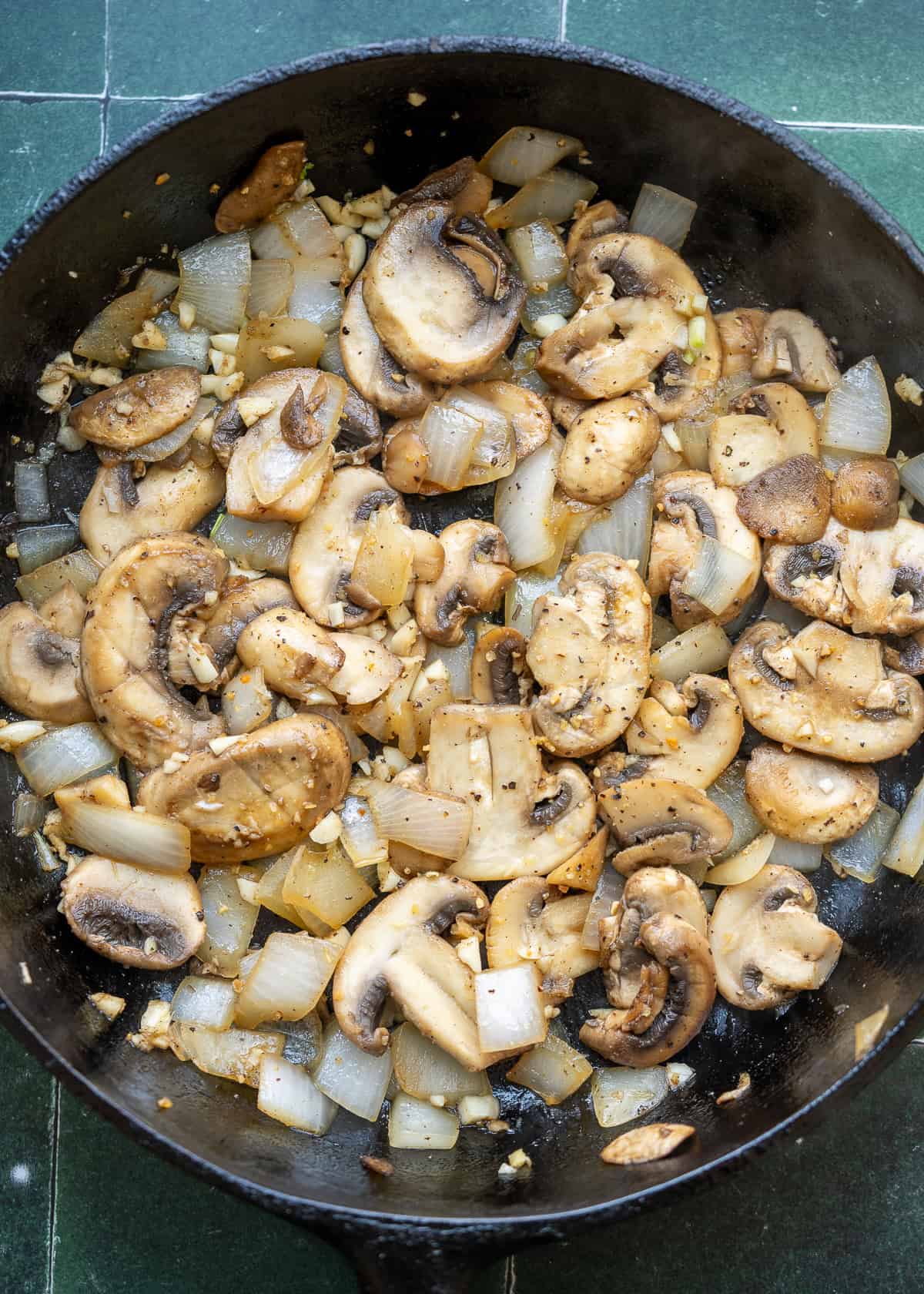 mushrooms being sauteed in cast iron skillet