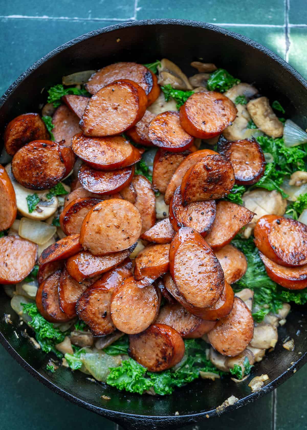 andouille sausage being added back to skillet with veggies to finish sausage and veggie skillet recipe