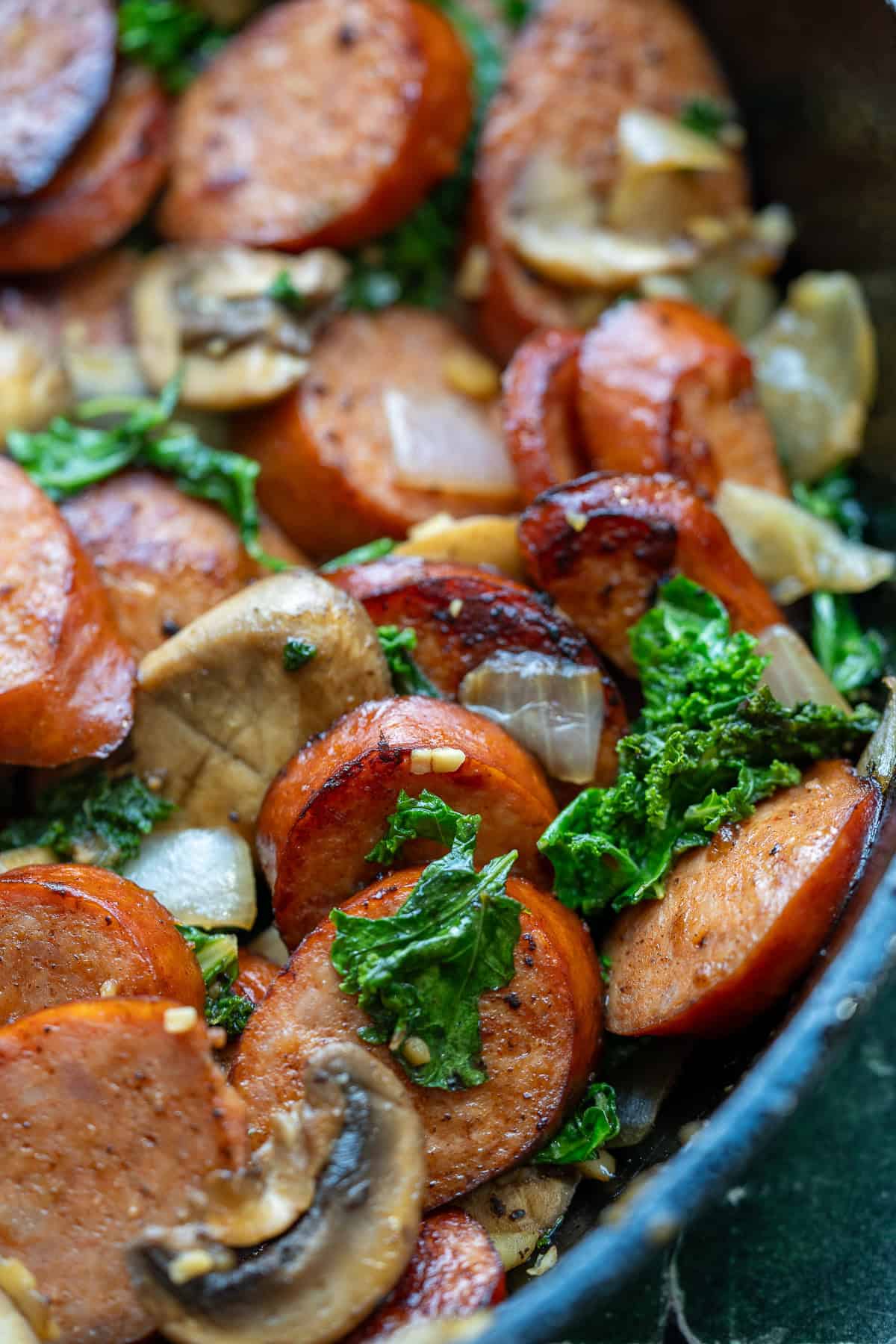 juicy andouille sausage in a skillet with vegetables
