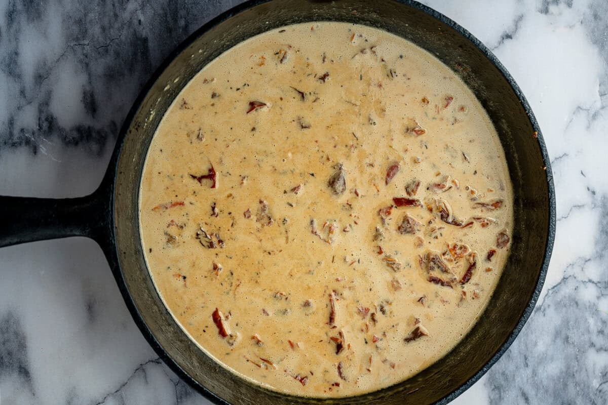 the creamy Tuscan sauce simmering in a cast iron skillet