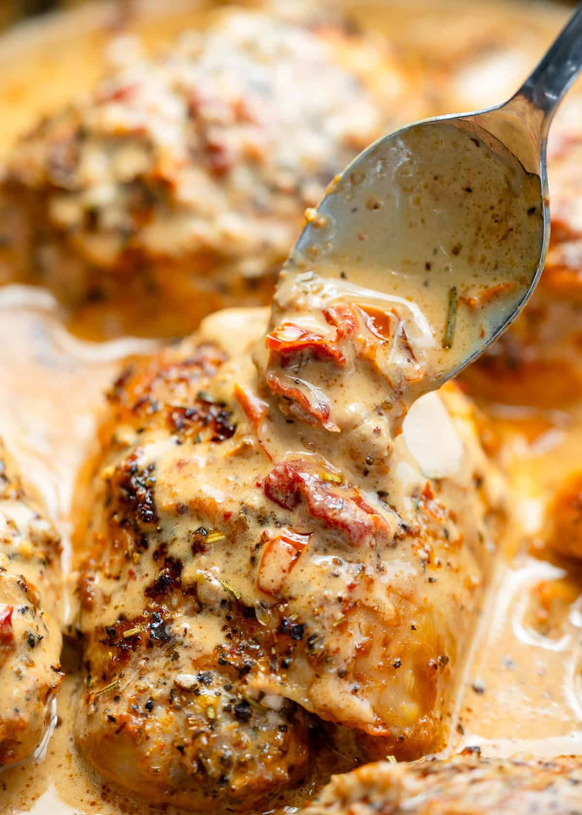 the creamy Tuscan sauce being drizzled over a chicken thigh