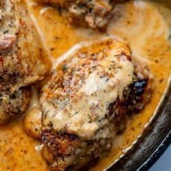 close up image of 3 chicken thighs in a creamy Tuscan sauce