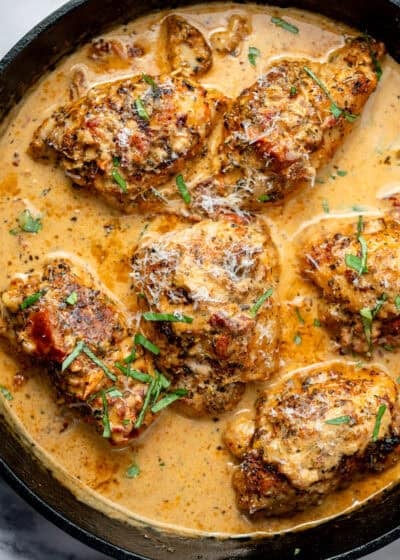 overhead image of tuscan chicken thighs in a cast iron skillet
